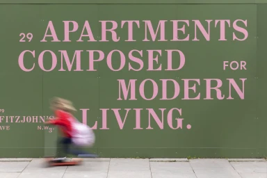 Motion-blurred child on scooter passing a large green hoarding with pink typography for Fitzjohn's brand identity