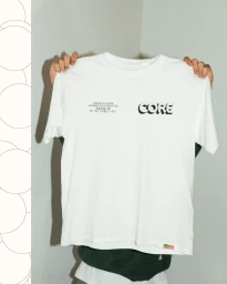 A person holding up a white t-shirt featuring the Core brand logo and Japanese typography against a plain grey background