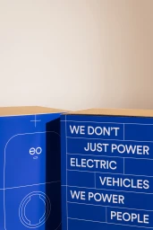 Blue branded packaging boxes with white typography against a neutral background for EO