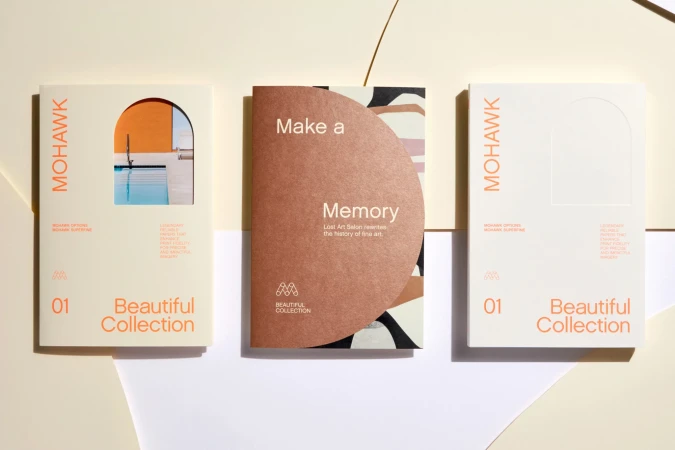 Three Mohawk paper sample books are arranged against a white backdrop, showcasing design elements and material quality.