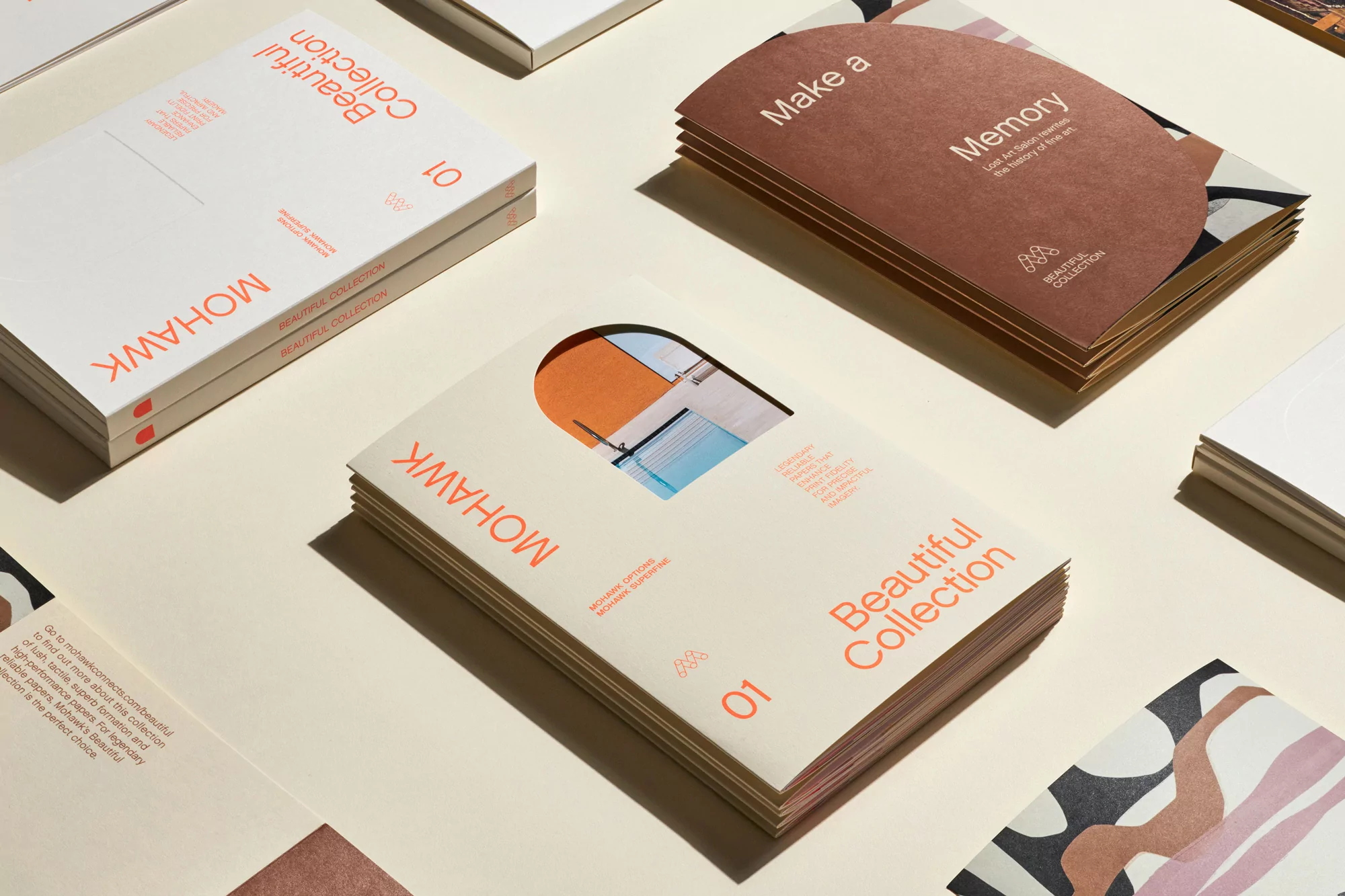 Promotional product photography showcasing Mohawk paper collections on a cream-colored surface with a bright, soft lighting style.
