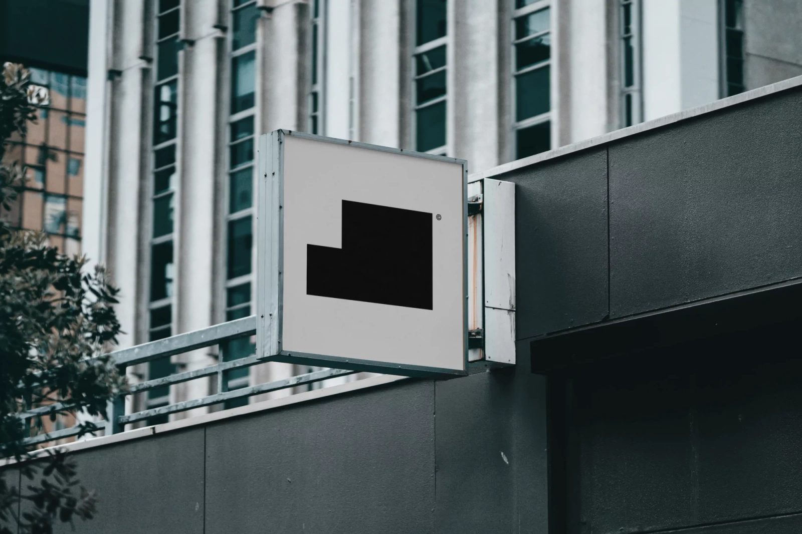 Square sign with a black geometric logo mounted on a modern building exterior