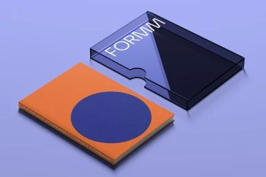 An orange book with a blue circular design next to a dark transparent box featuring white FORMM branding on a light purple surface.