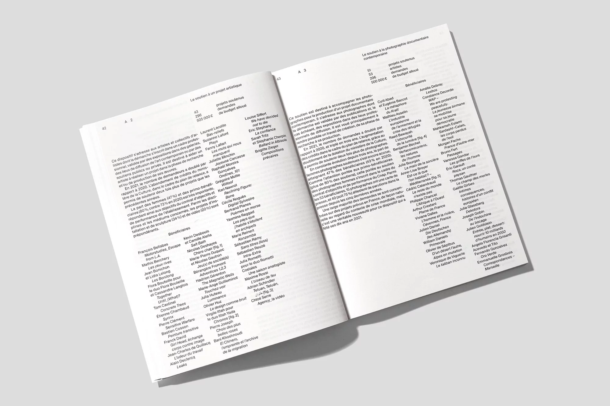 Open book displays text-filled pages in a close-up shot, revealing detailed typography and page layout against a plain backdrop.