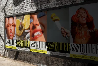 Outdoor advertising billboard featuring multiple panels displaying lemon slices, close-up portraits, and bold typography for StillBitter.