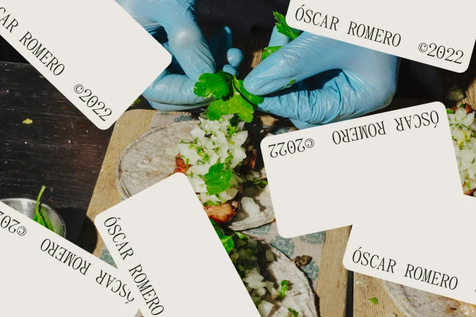 Close-up of tacos being garnished with cilantro by hands in blue gloves, featuring an overhead angle, wooden surface, and bright daylight.