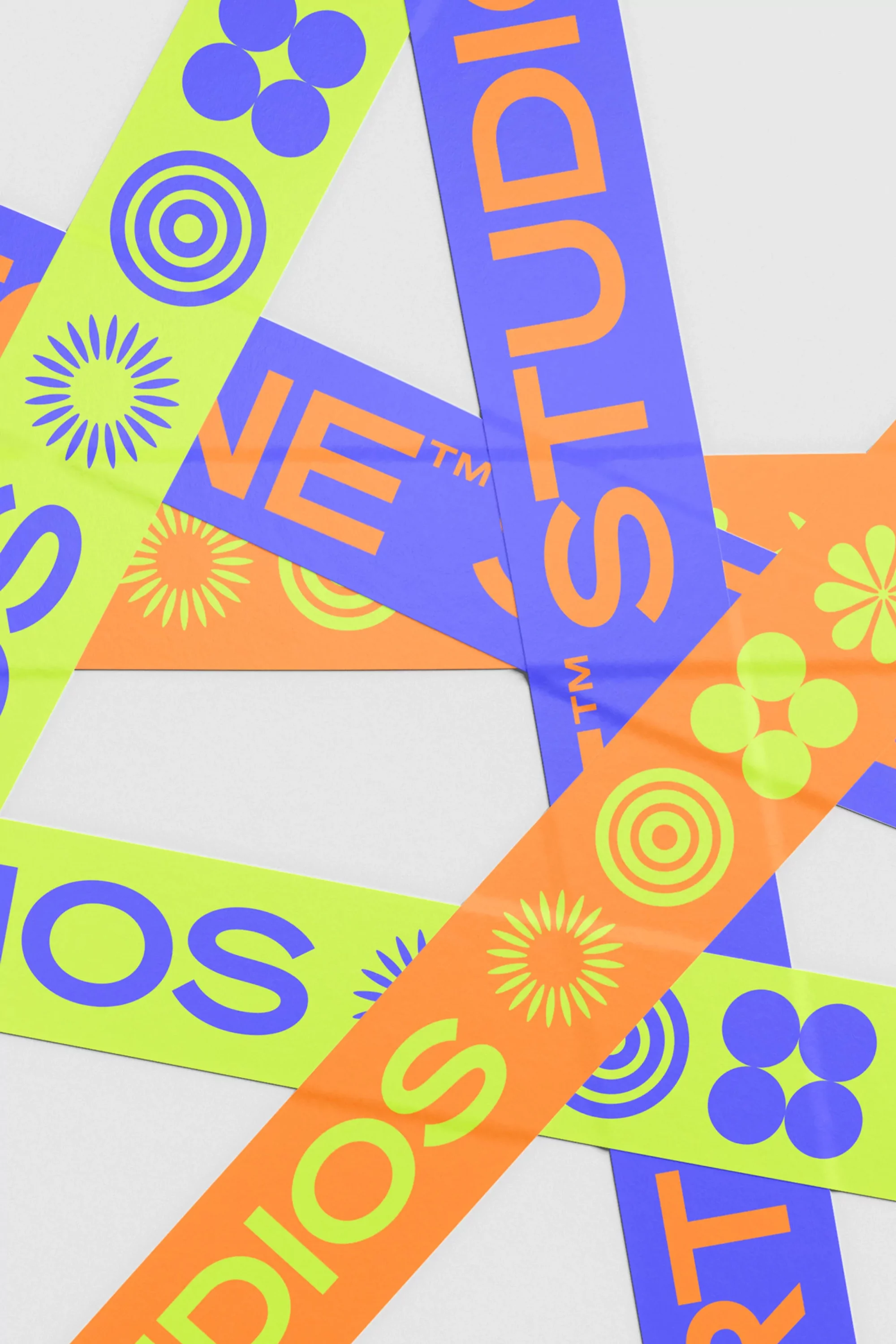 Colorful ribbons with text and geometric patterns overlay a white surface in a studio-style shot.  Geometric shapes and bright colors.