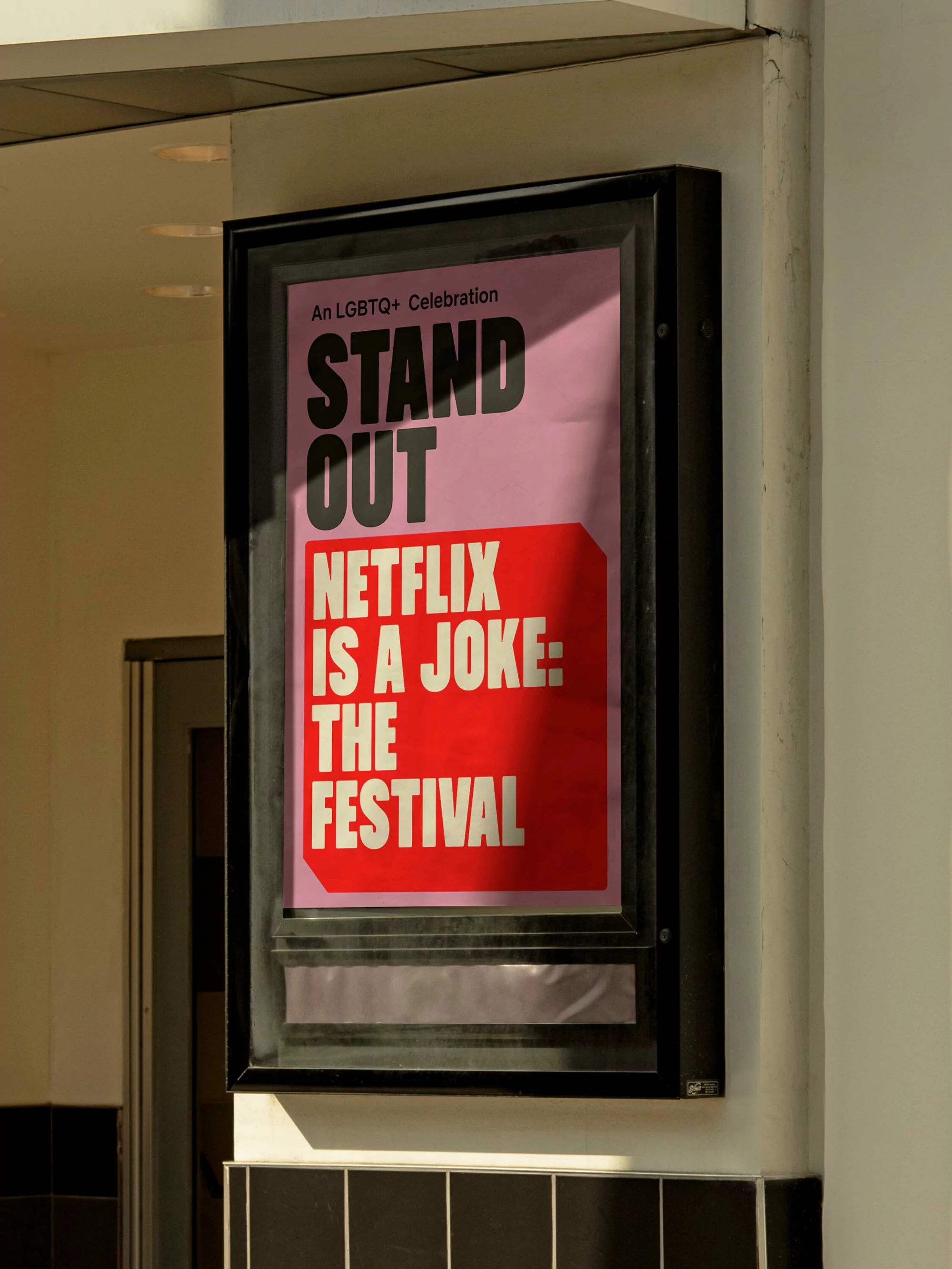 Outdoor poster for Netflix is a Joke: The Festival featuring stand out lettering with pink background and black frame in natural light.