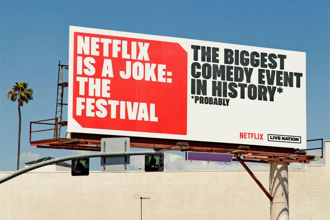 Outdoor billboard advertisement for the Netflix Is A Joke comedy festival, set against a clear blue sky in an urban environment.