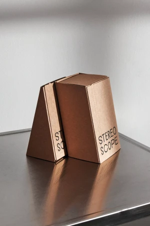 Two brown cardboard packaging boxes with custom typography resting on a metallic surface