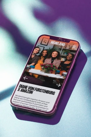 Smartphone screen displays four women, branding for Newland, and text promoting a partnership between Diane von Furstenburg and Amazon.