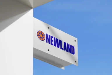 White Newland brand identity sign mounted on a building exterior against a clear blue sky