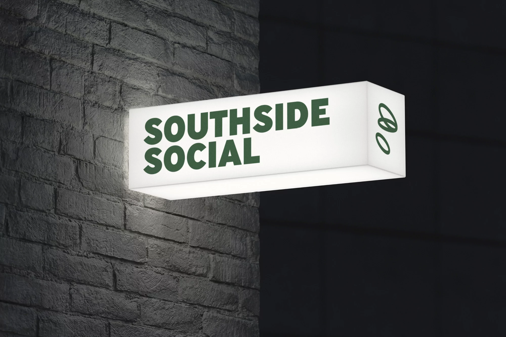 Illuminated sign reading 'Southside Social' mounted on a textured grey brick wall, casting a warm glow in a dimly lit environment.