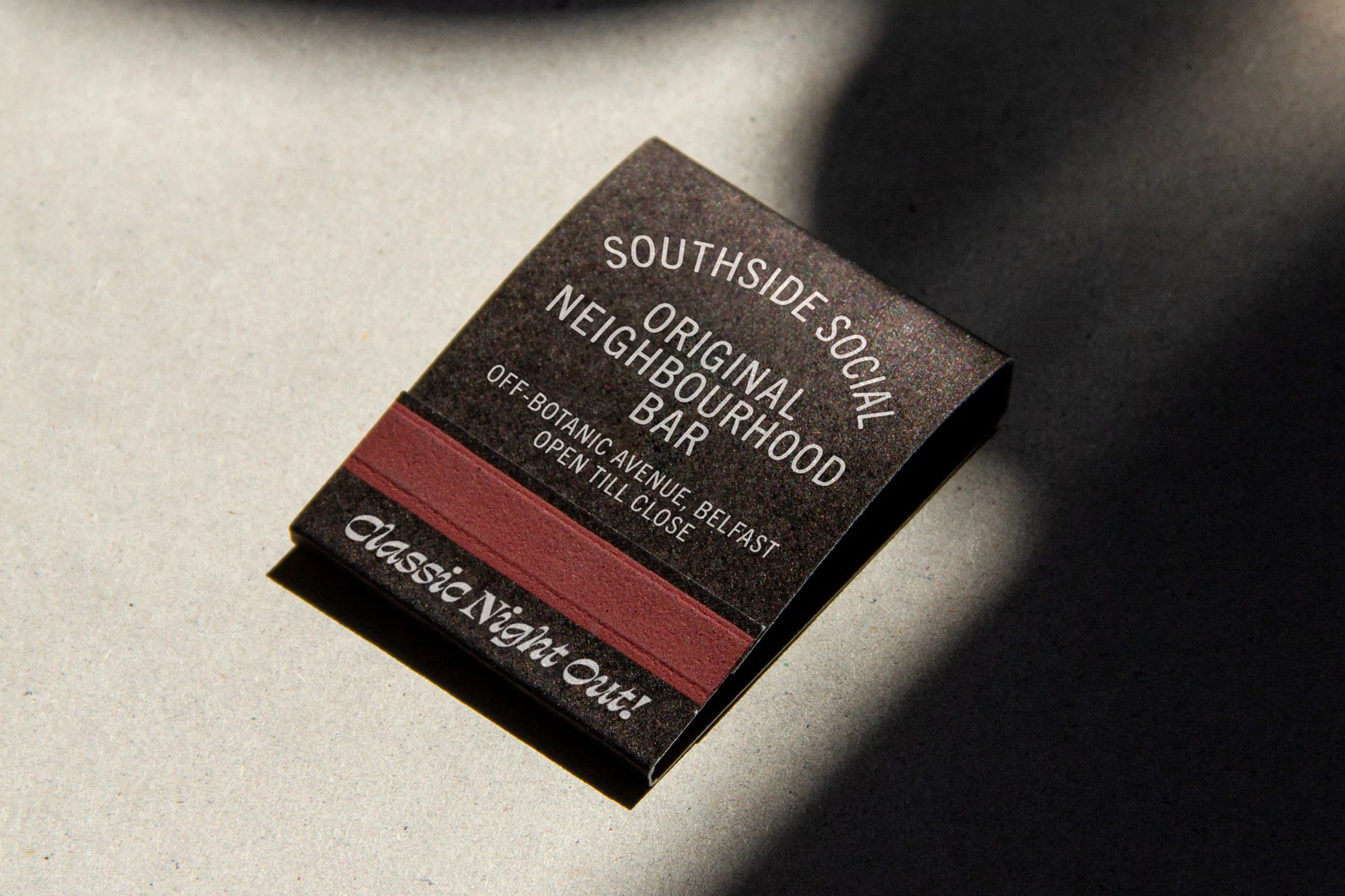 Close-up of a black matchbook with white text, advertising Southside Social Neighborhood Bar in Belfast, with a classic night out theme.