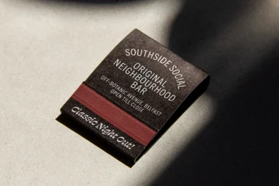 Close-up of a branded matchbox for Southside Social resting on a textured grey paper background under angled light