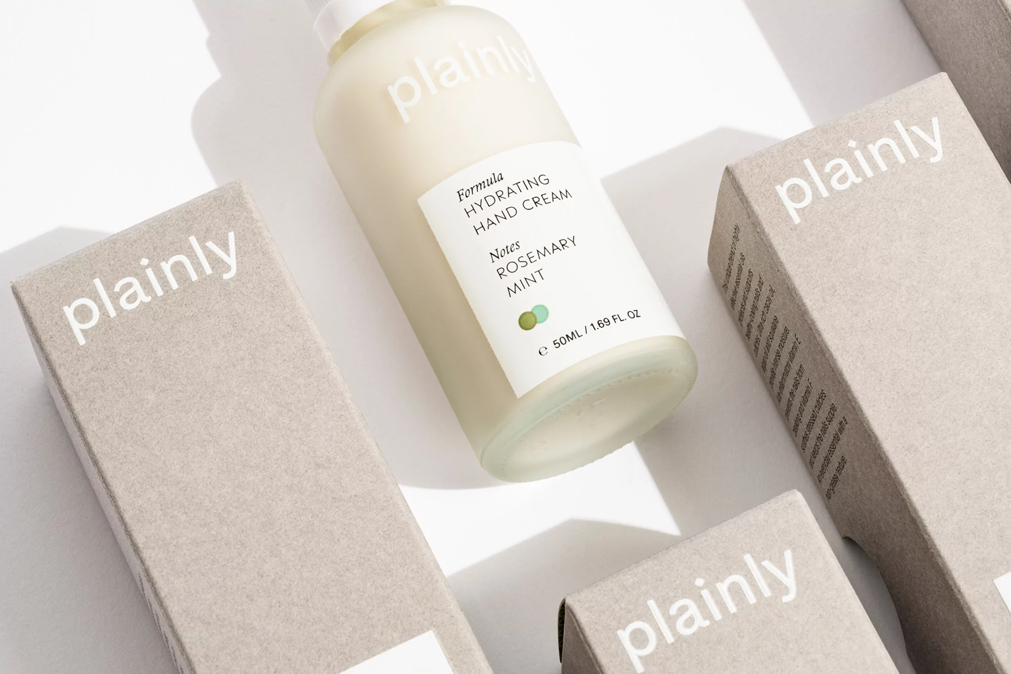 Plainly brand hydrating hand cream and packaging featuring rosemary and mint notes on a bright, clean surface in a beauty product still life.