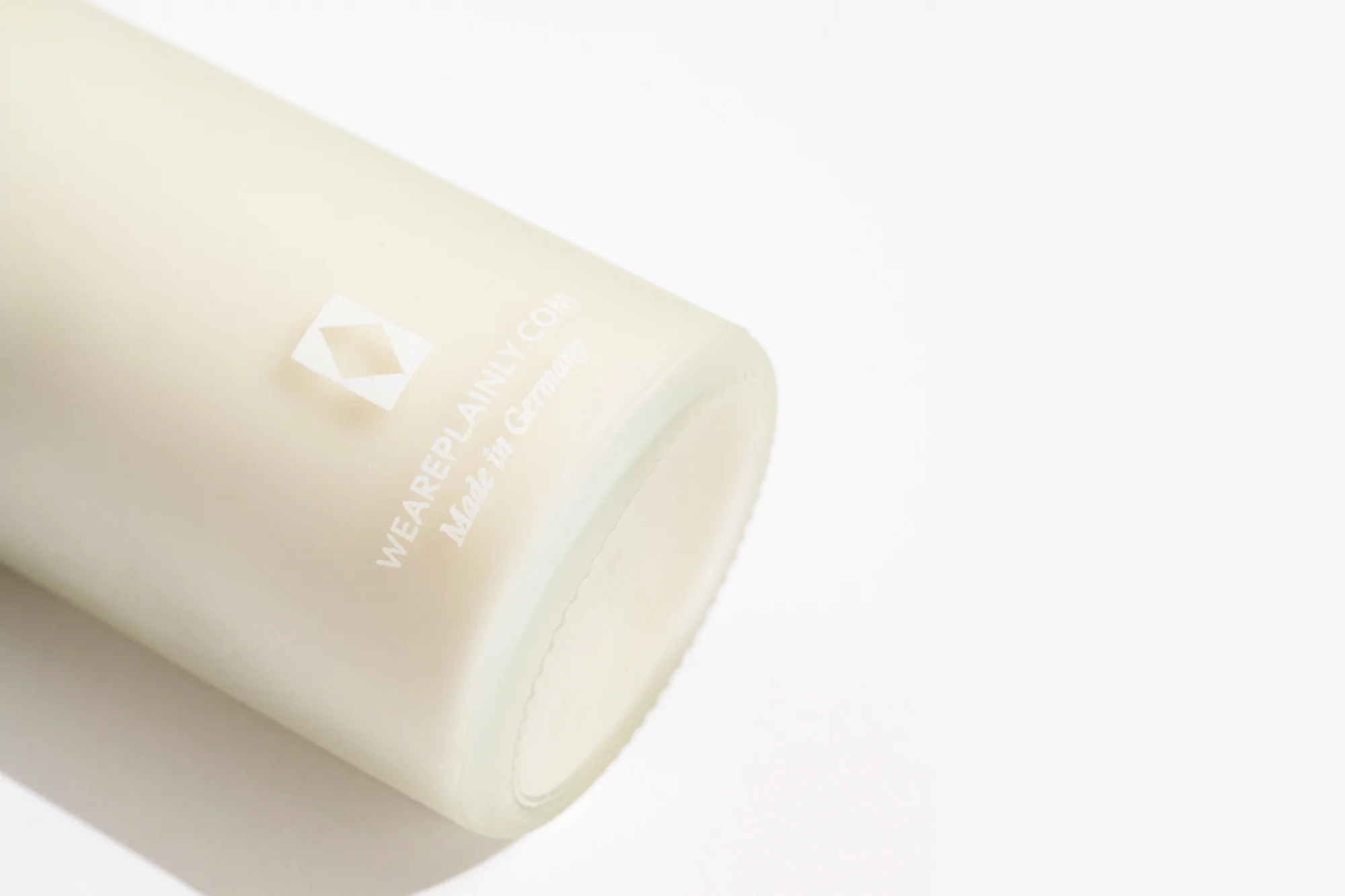 Frosted glass bottle with a geometric logo and brand name text in bright studio lighting against a white background. Product shot.