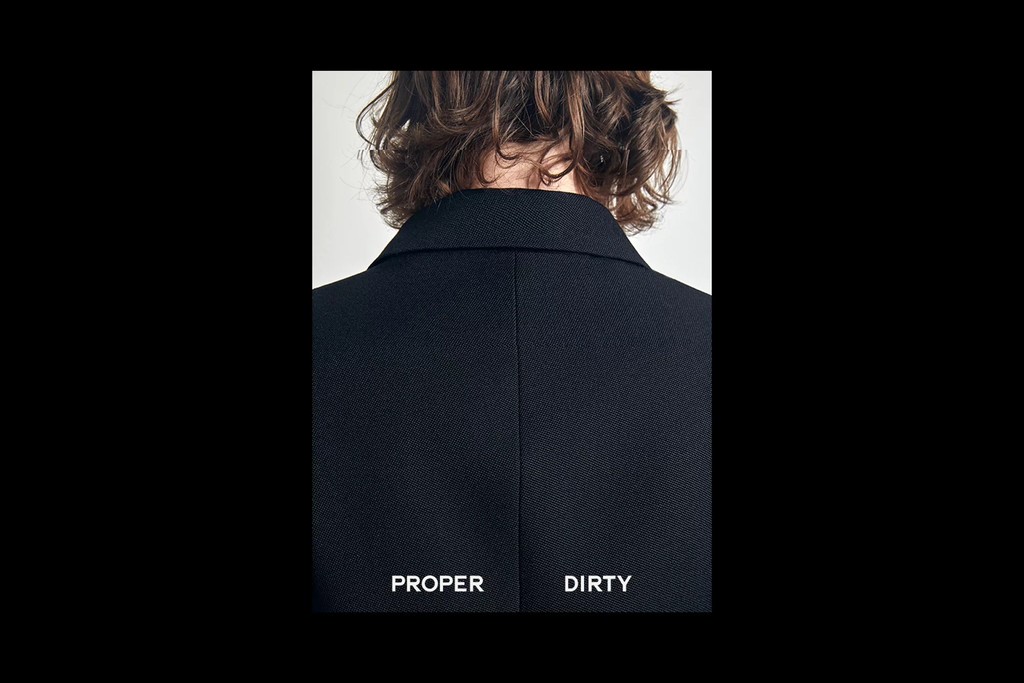Close-up of the back of a person with wavy brown hair wearing a dark blazer against a white background in a studio setting.