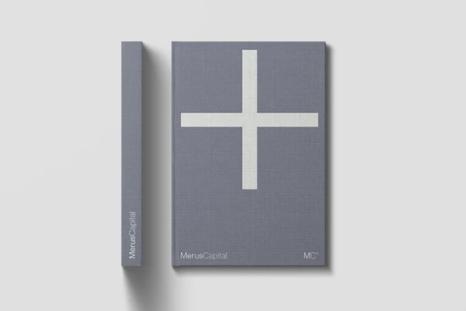 Two hardcover books, gray with a large white plus sign, rest on a clean white surface in a minimalist composition.