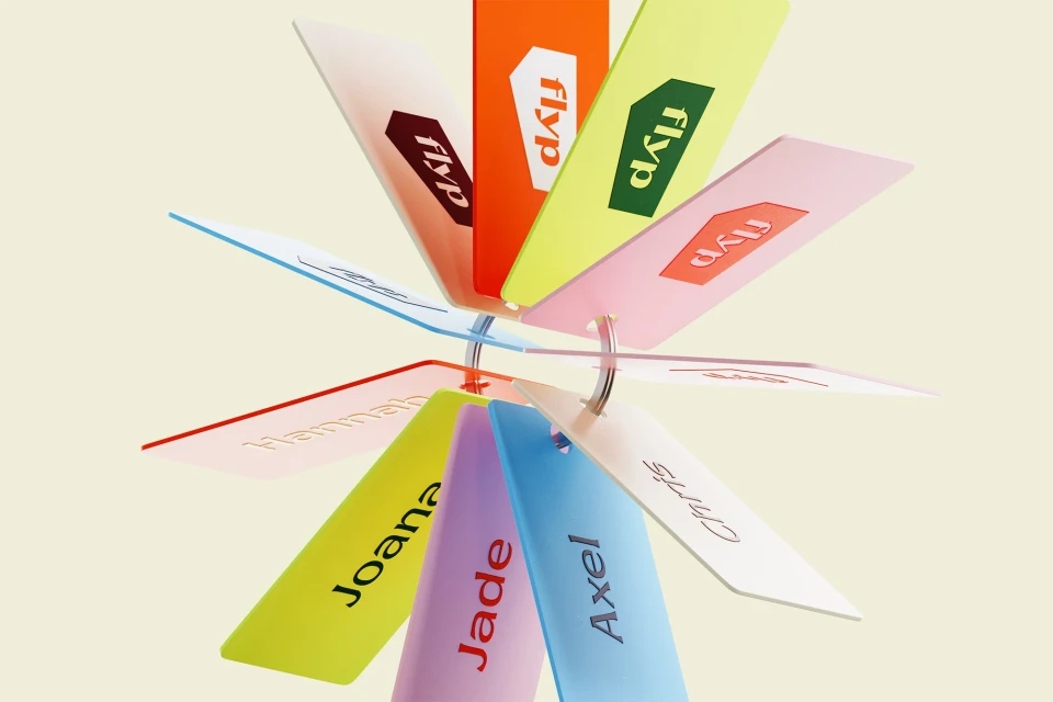 Colorful tags with names and the 'flyp' logo, arranged in a circular pattern on a light yellow background, create a vibrant and playful image.
