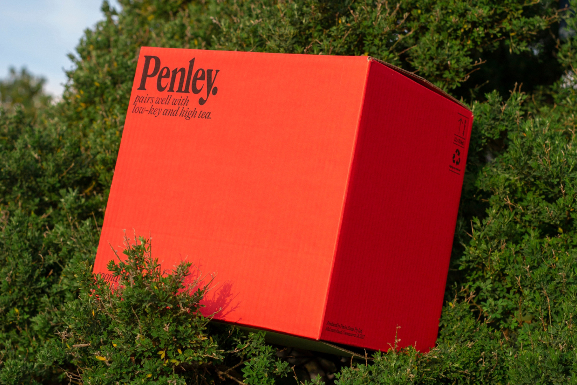 Red Penley brand box sits within lush green foliage in an outdoor setting, creating a visually striking contrast with clear sky backdrop.
