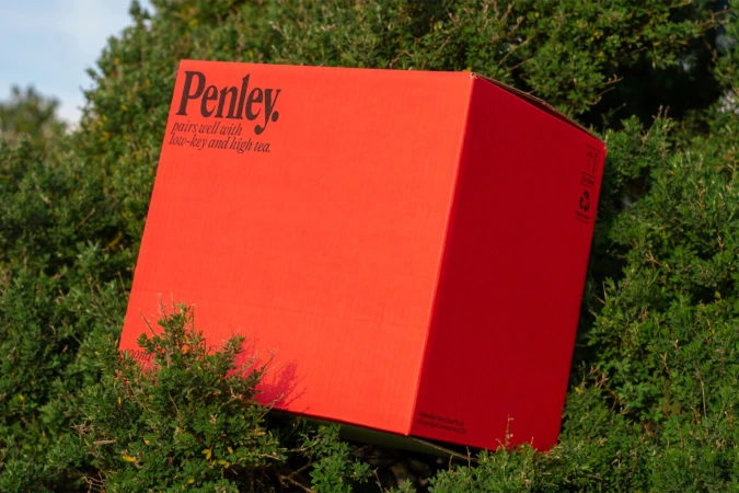 Red Penley brand box sits within lush green foliage in an outdoor setting, creating a visually striking contrast with clear sky backdrop.