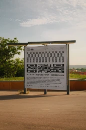 Large outdoor advertising poster with bold black and white graphic patterns mounted on a metal structure.