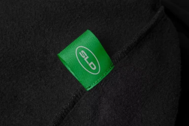 Close-up of a green fabric label with white text reading SLD stitched into dark textured material