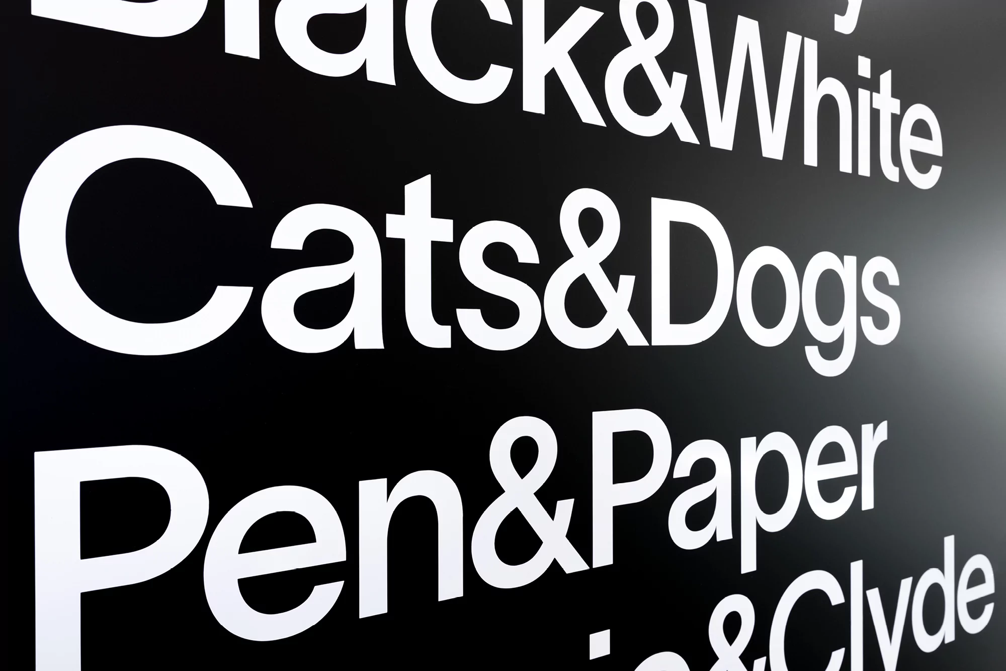 Graphic image features a black background with white text phrases: 'Black & White,' 'Cats & Dogs,' 'Pen & Paper' creating a striking contrast.