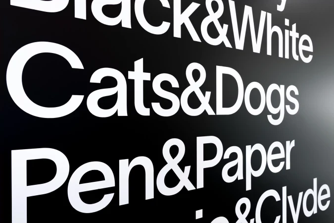 Graphic image features a black background with white text phrases: 'Black & White,' 'Cats & Dogs,' 'Pen & Paper' creating a striking contrast.