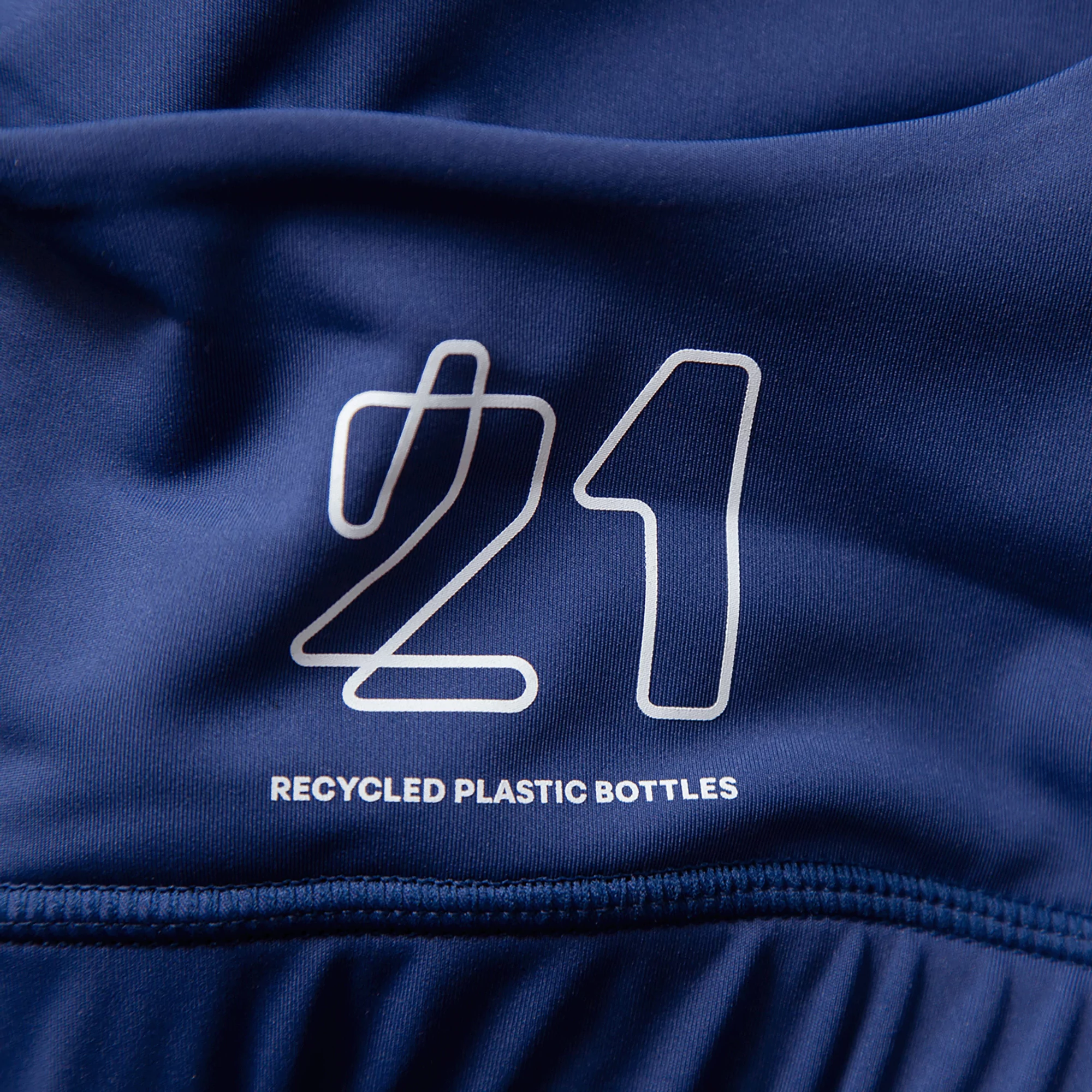 Close-up of navy blue athletic apparel with a white '21' graphic and the text 'Recycled Plastic Bottles' indicating sustainability.