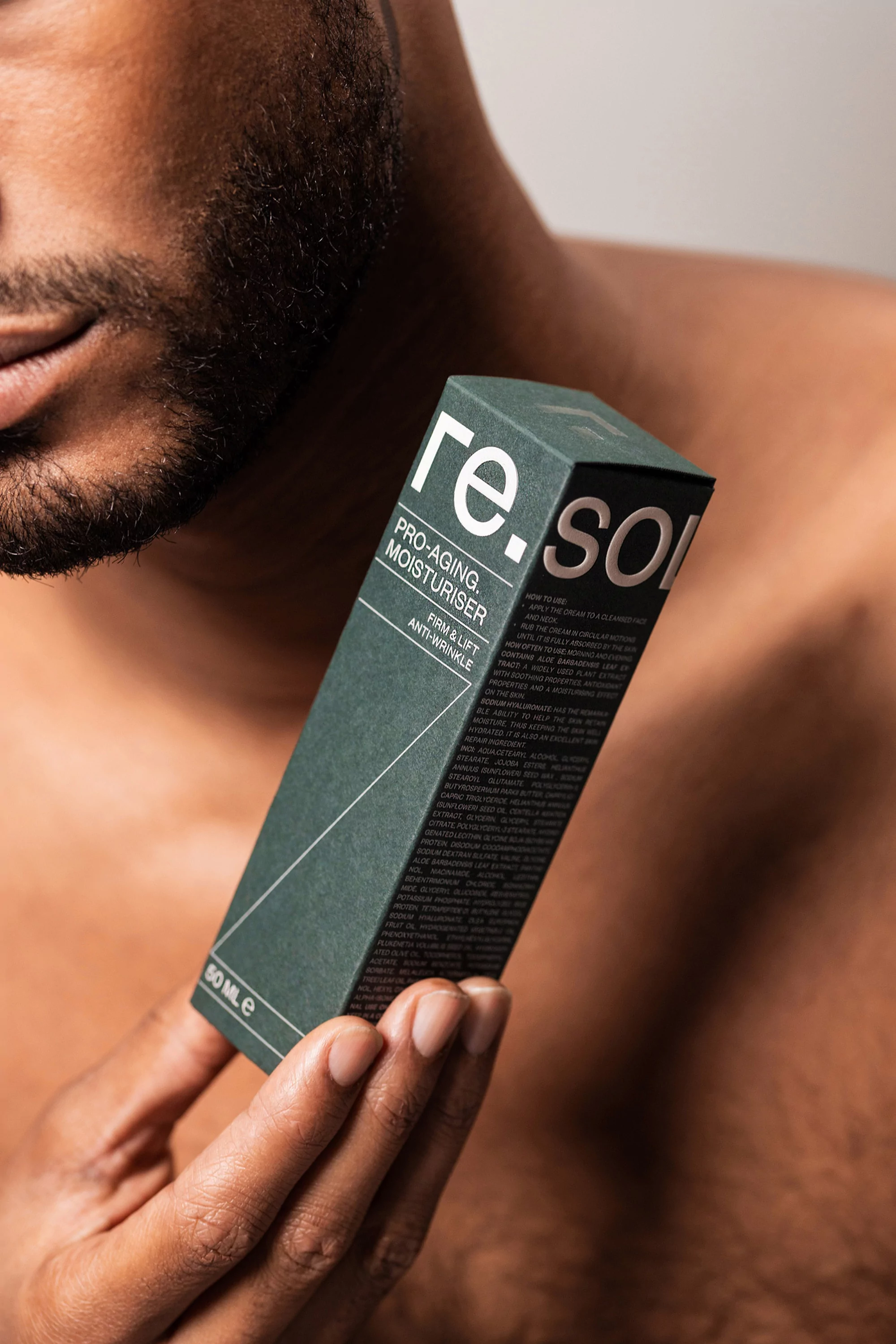Adult male displaying a re.source skincare product box in a studio setting, showcasing the product and brand against a neutral background.