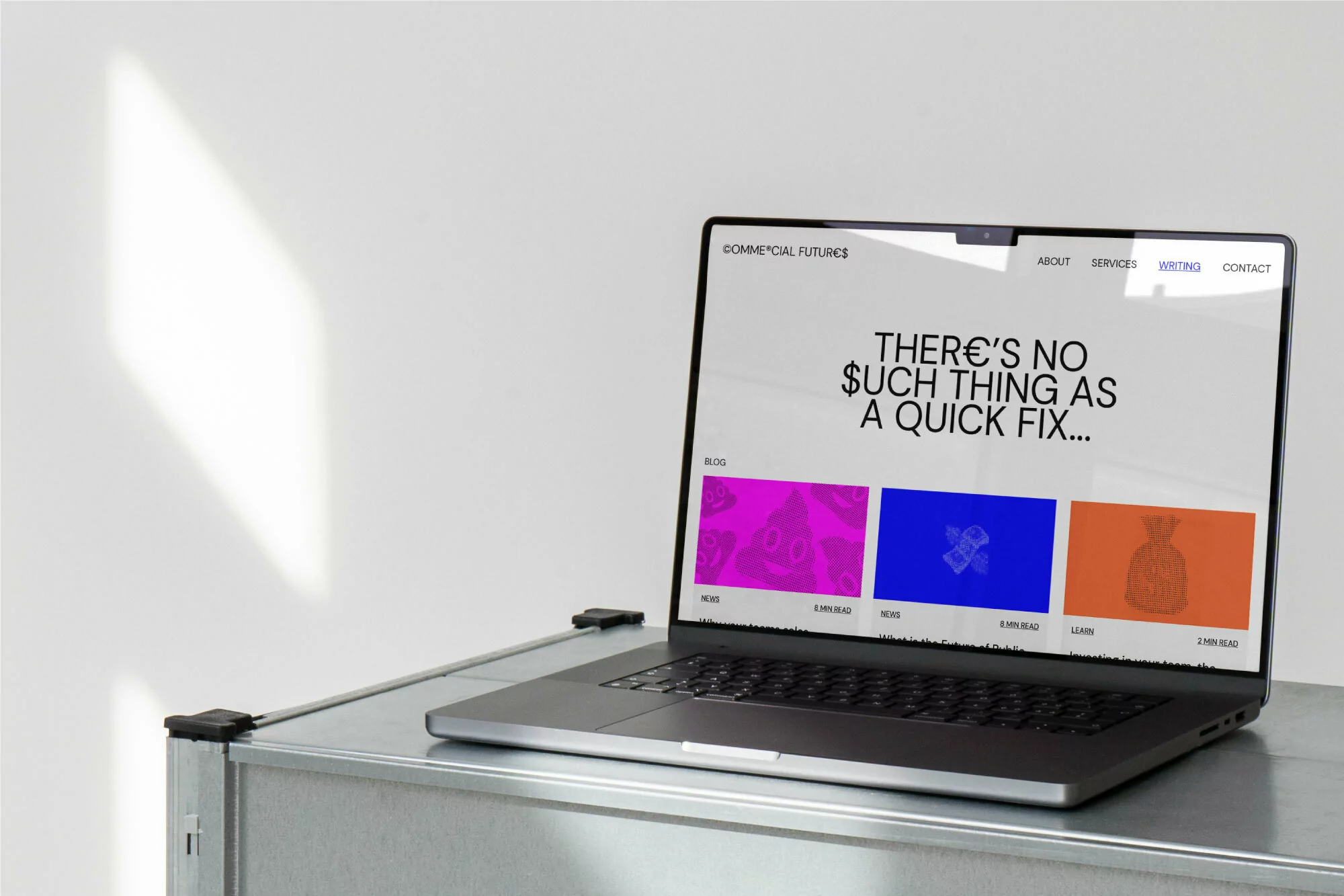 A laptop displaying a website with the text 'There's no such thing as a quick fix...' sits on a metal surface with a white wall behind it.