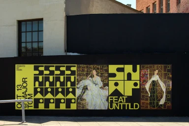 SNAP brand identity posters featuring bold yellow typography and fashion imagery displayed on an outdoor black construction wall