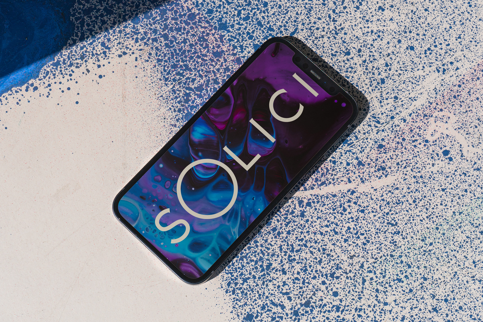Modern smartphone displaying SOLICI branding on a purple and blue abstract background atop a splattered paint surface with dynamic shadow.