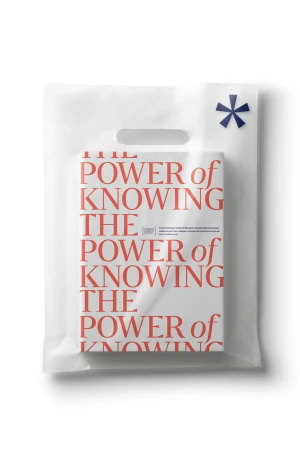 A book titled 'The Power of Knowing' inside of a white plastic shopping bag against a white backdrop. Focus on the book's design.