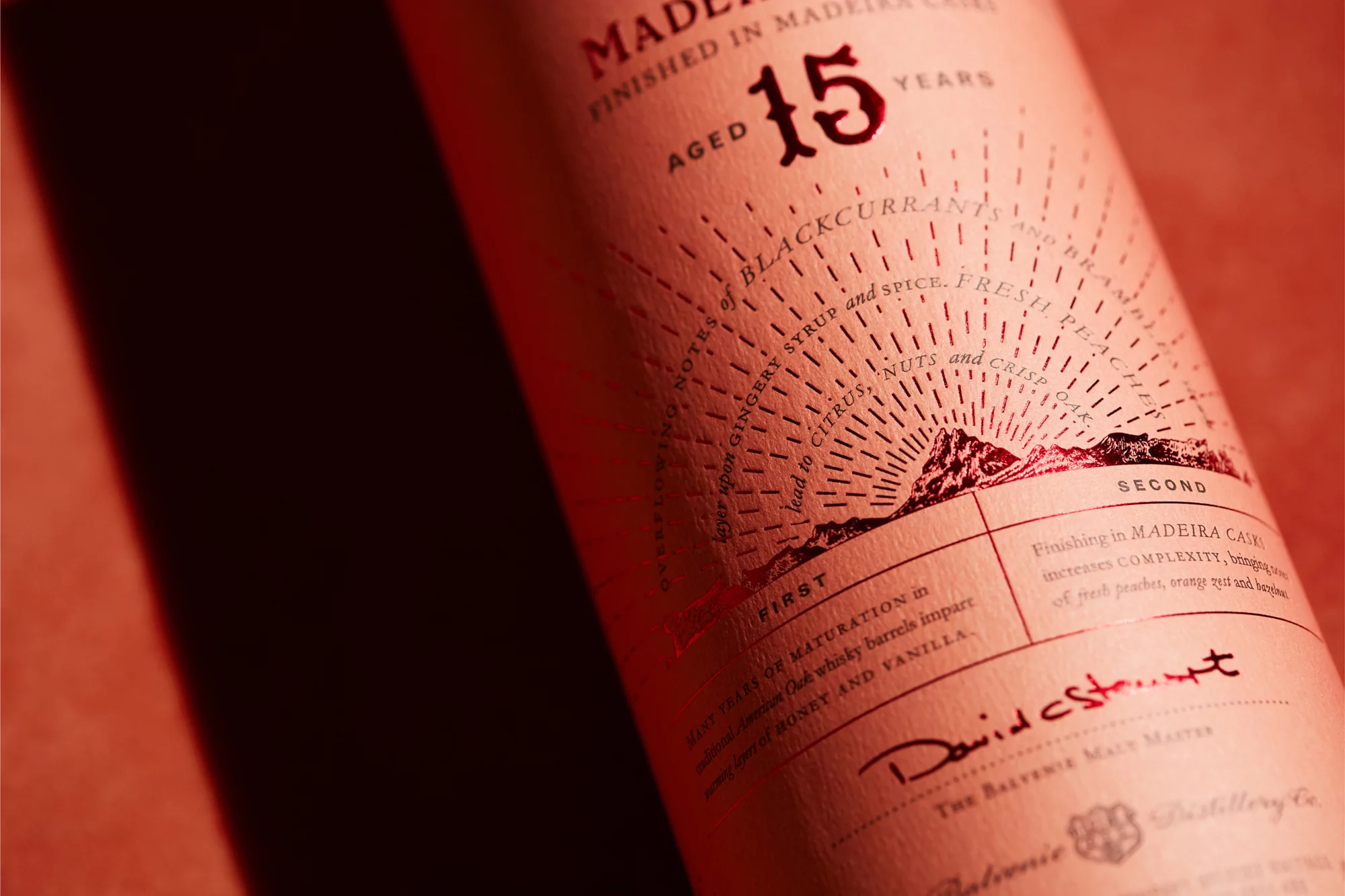 Close-up photograph of a bottle of The Balvenie Madeira Cask aged 15 years, with flavor notes such as blackcurrant, ginger, citrus, and vanilla.