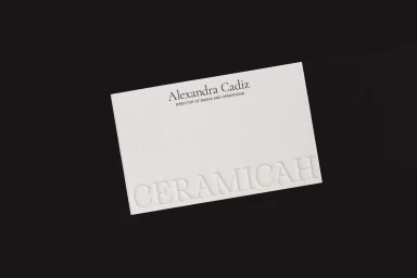 White textured business card for Ceramicah featuring embossed typography on a dark background