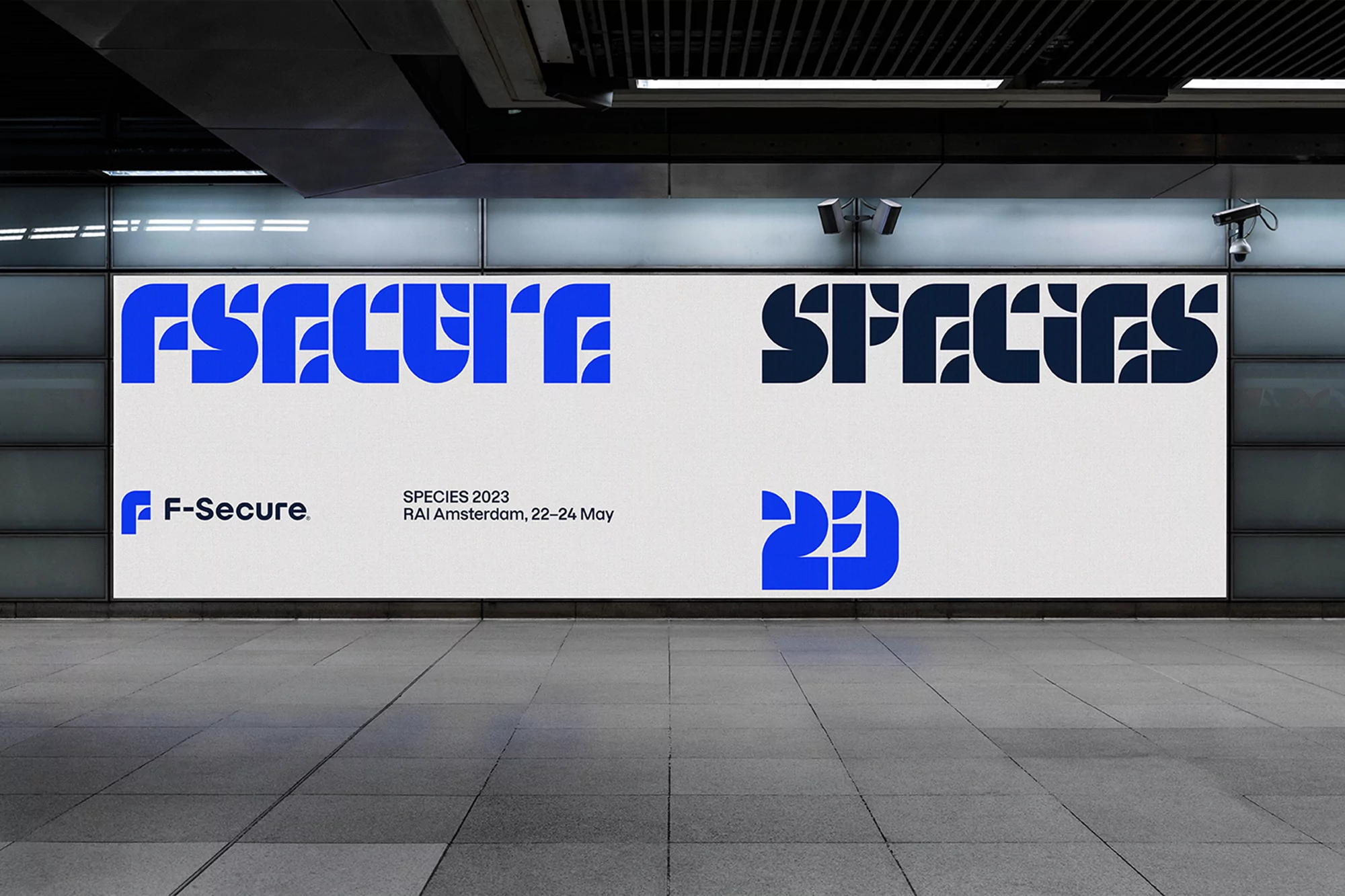 F-Secure cybersecurity billboard advertisement in a subway station, featuring bold typography, blue and white colors, promoting a 2023 event.