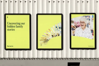 Three vertical black-framed posters mounted on a vertically ribbed white exterior wall, featuring bright yellow branding and photography.