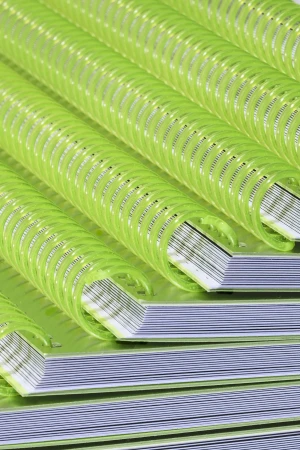 Close-up on a stack of notebooks featuring a spiral binding made of light green plastic. The notebooks are stacked, creating a pattern.