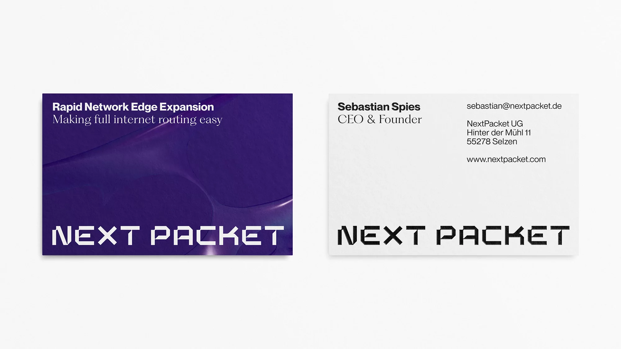 Two business cards side by side, with the name "NEXT PACKET" prominently displayed in a stylized font on both, one with a purple design.