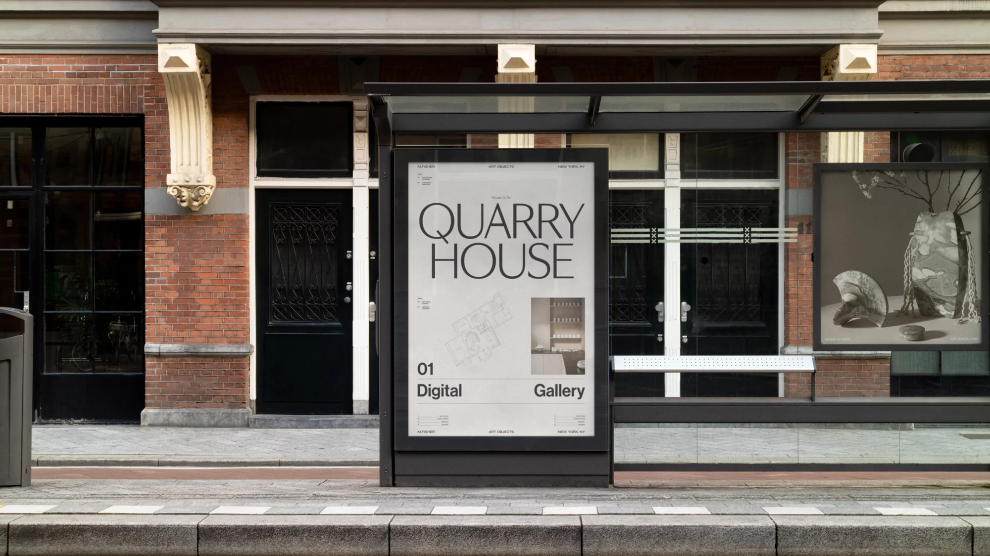 Street-level view of a bus stop shelter displaying posters with modern typography and design elements on a brick-building backdrop.