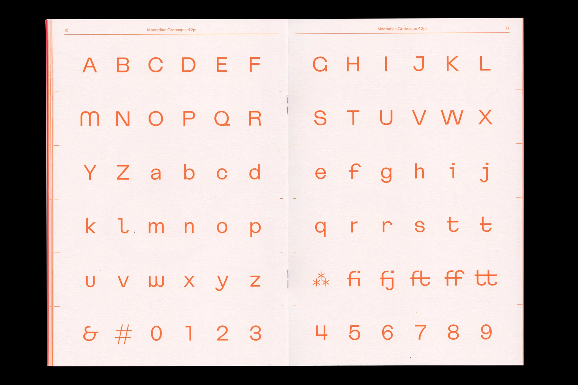 Open book displaying orange sans-serif typeface including uppercase and lowercase letters, numbers, and punctuation. Typography resource.