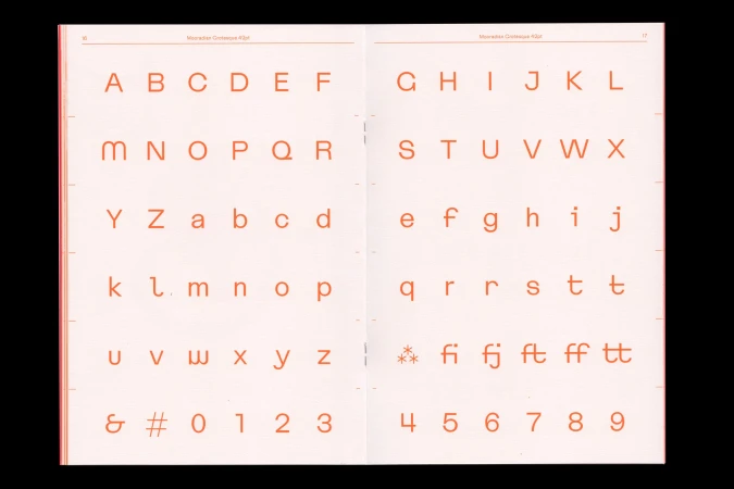Open book displaying orange sans-serif typeface including uppercase and lowercase letters, numbers, and punctuation. Typography resource.