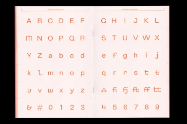 Spread of a typography specimen book showing alphabet letters in an orange sans-serif typeface on a pale cream paper background.