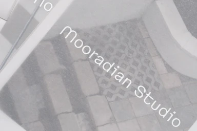 Close-up of translucent frosted paper overlaying textured stone pavers with the text mooradian studio printed clearly on top