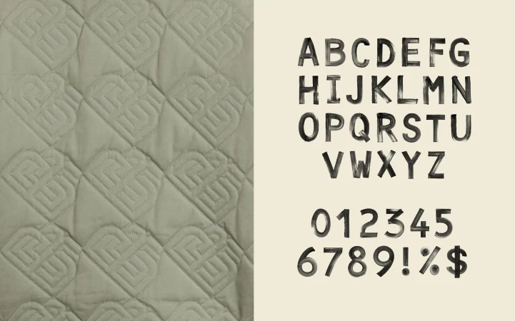 Textural image featuring a quilted fabric pattern with repeating logo designs, alongside an alphabet and number set displayed in a grunge font.