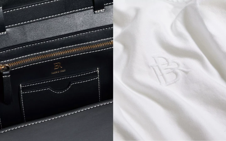 Close-up of a black leather tote bag interior with gold zipper and brand logo, contrasted with a white fabric swatch showing an embossed logo.