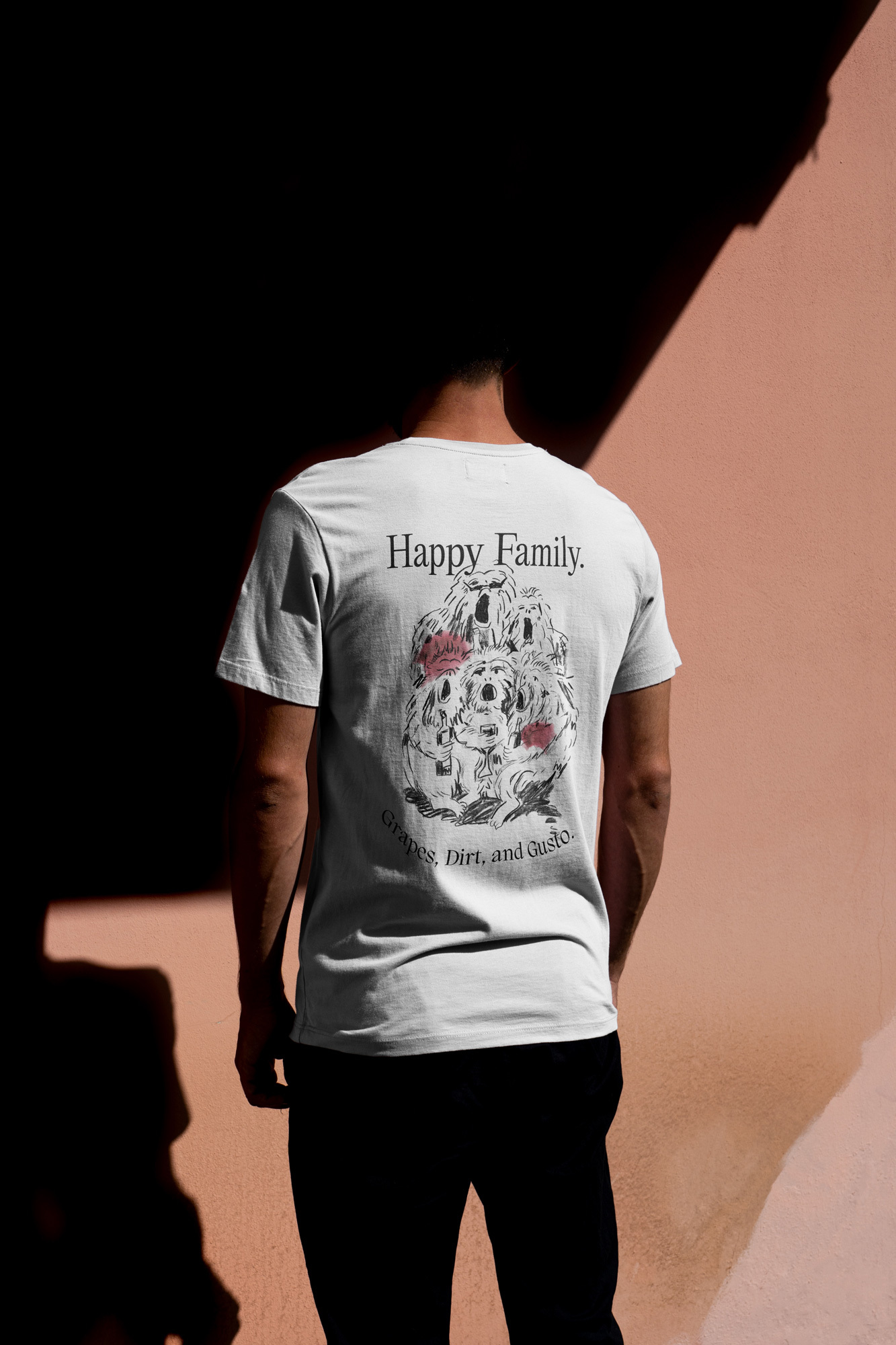 Person wearing a white t-shirt with a dog illustration and the text 'Happy Family' on the back, standing against a wall with strong shadow.